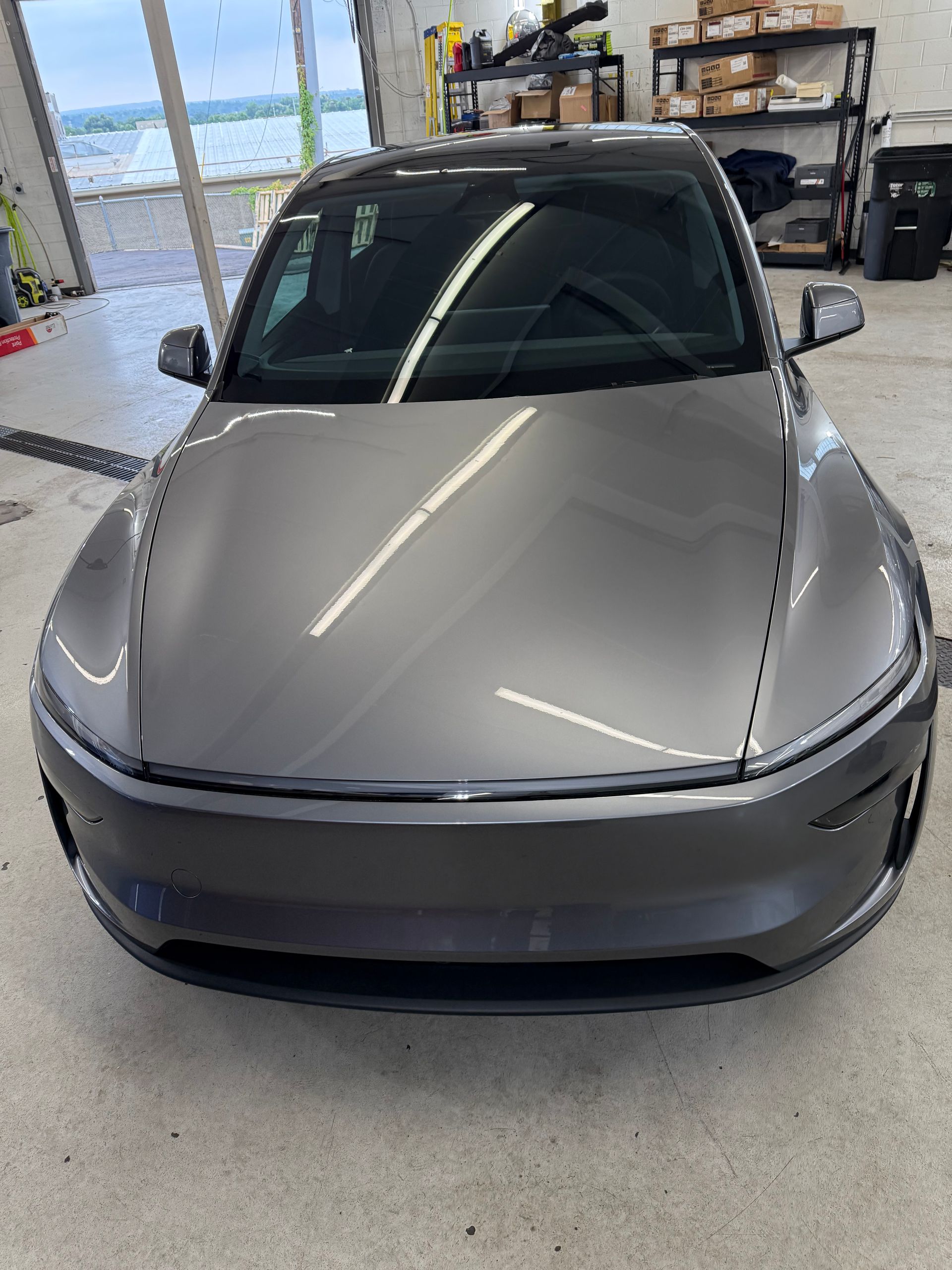 Gray electric car parked indoors, front view. Reflective surface, shiny paint.