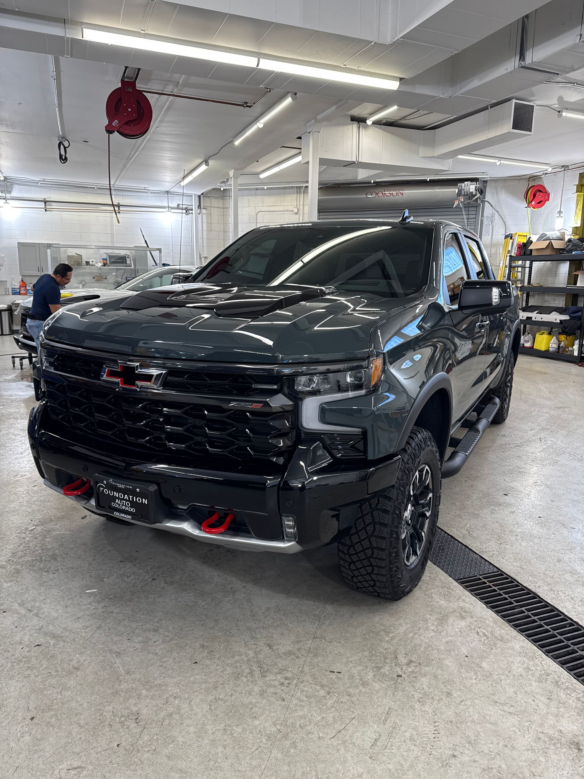 Dark green Chevrolet Silverado truck in a bright shop.