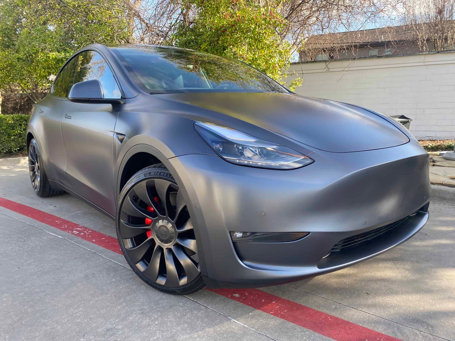 Black Cadillac SUV with matte finish, parked inside a garage, with black wheels.