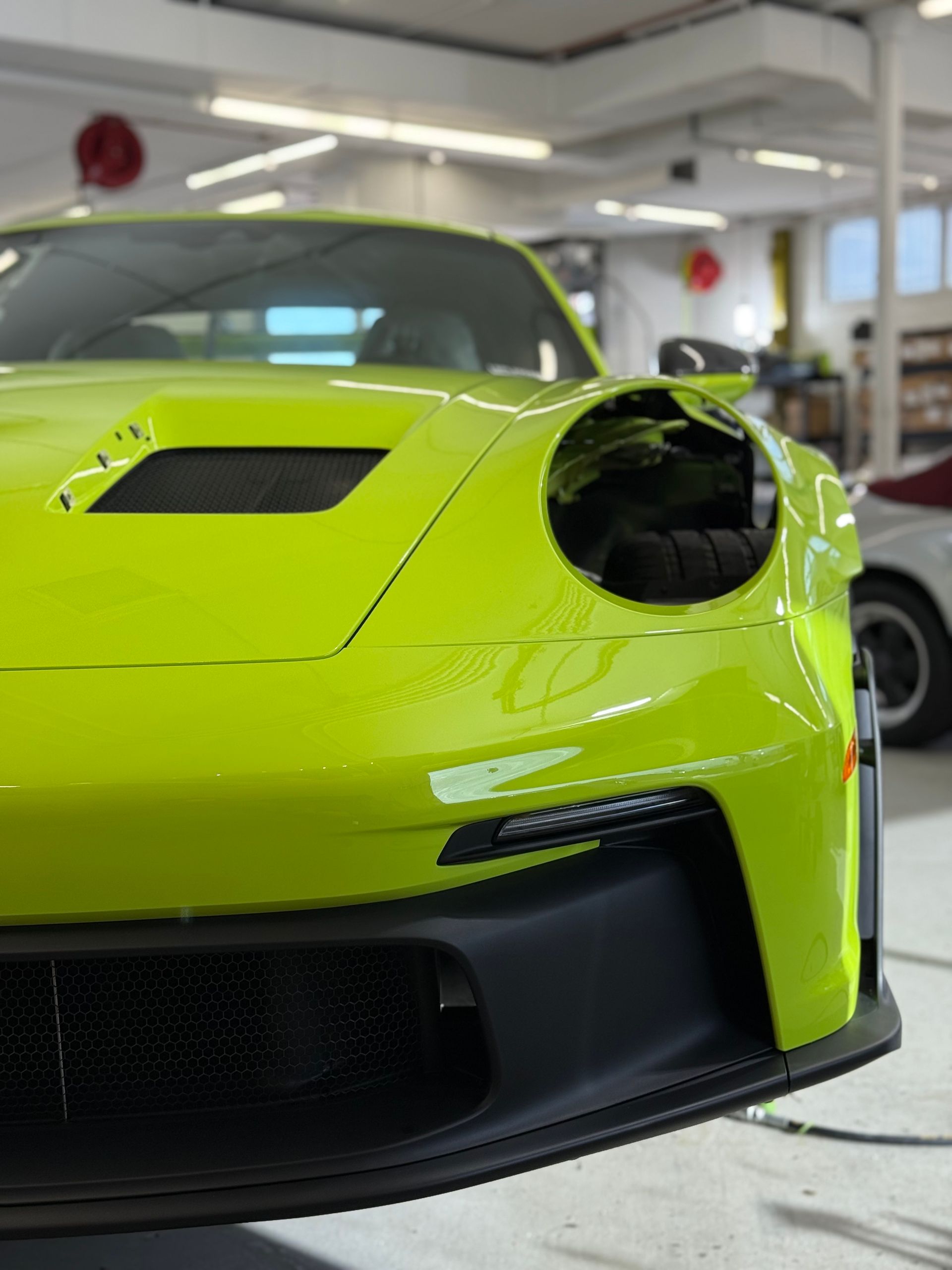 Bright green Porsche sports car, front view, in a garage.