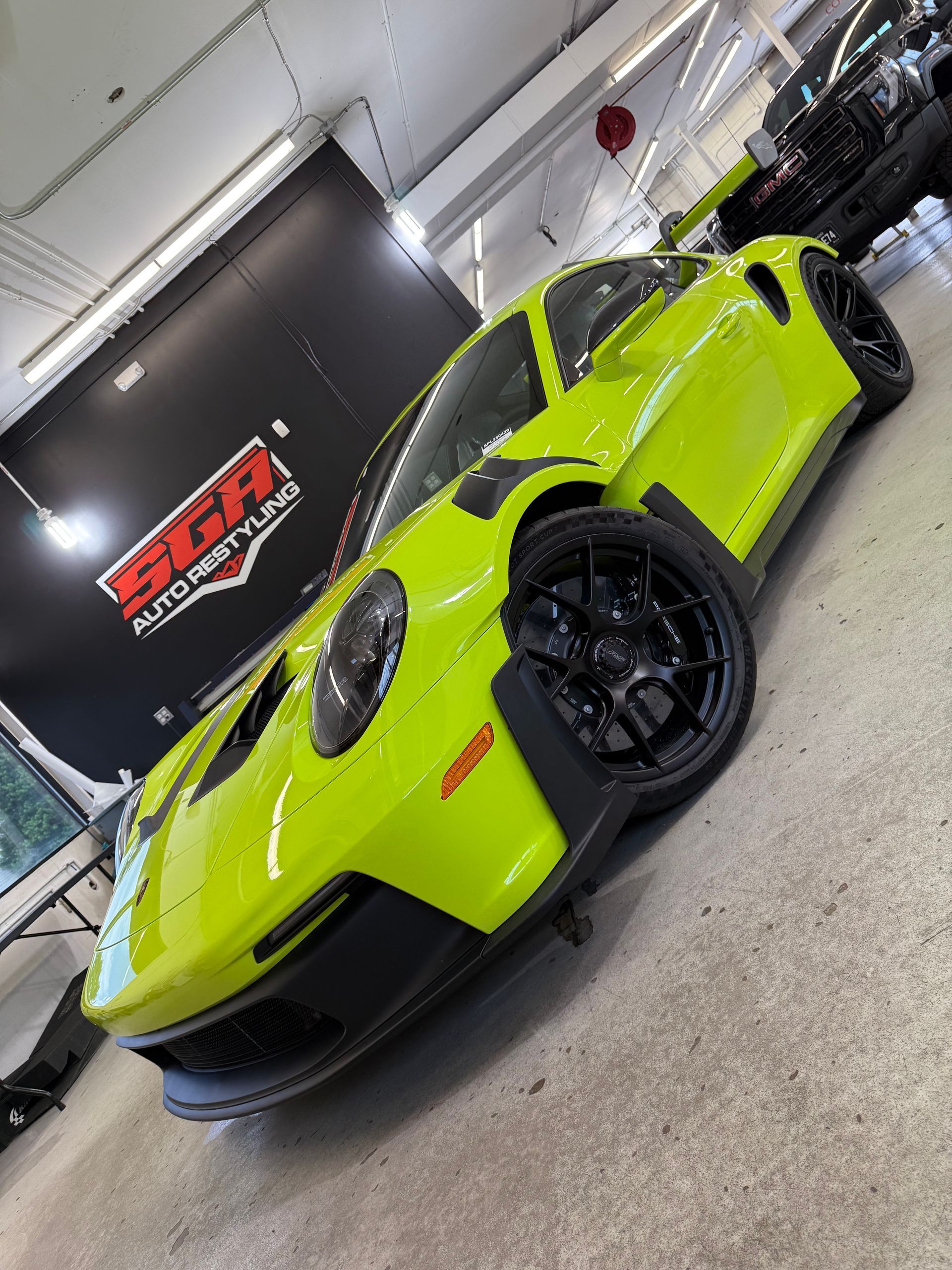 Bright green Porsche sports car with black wheels in a garage.