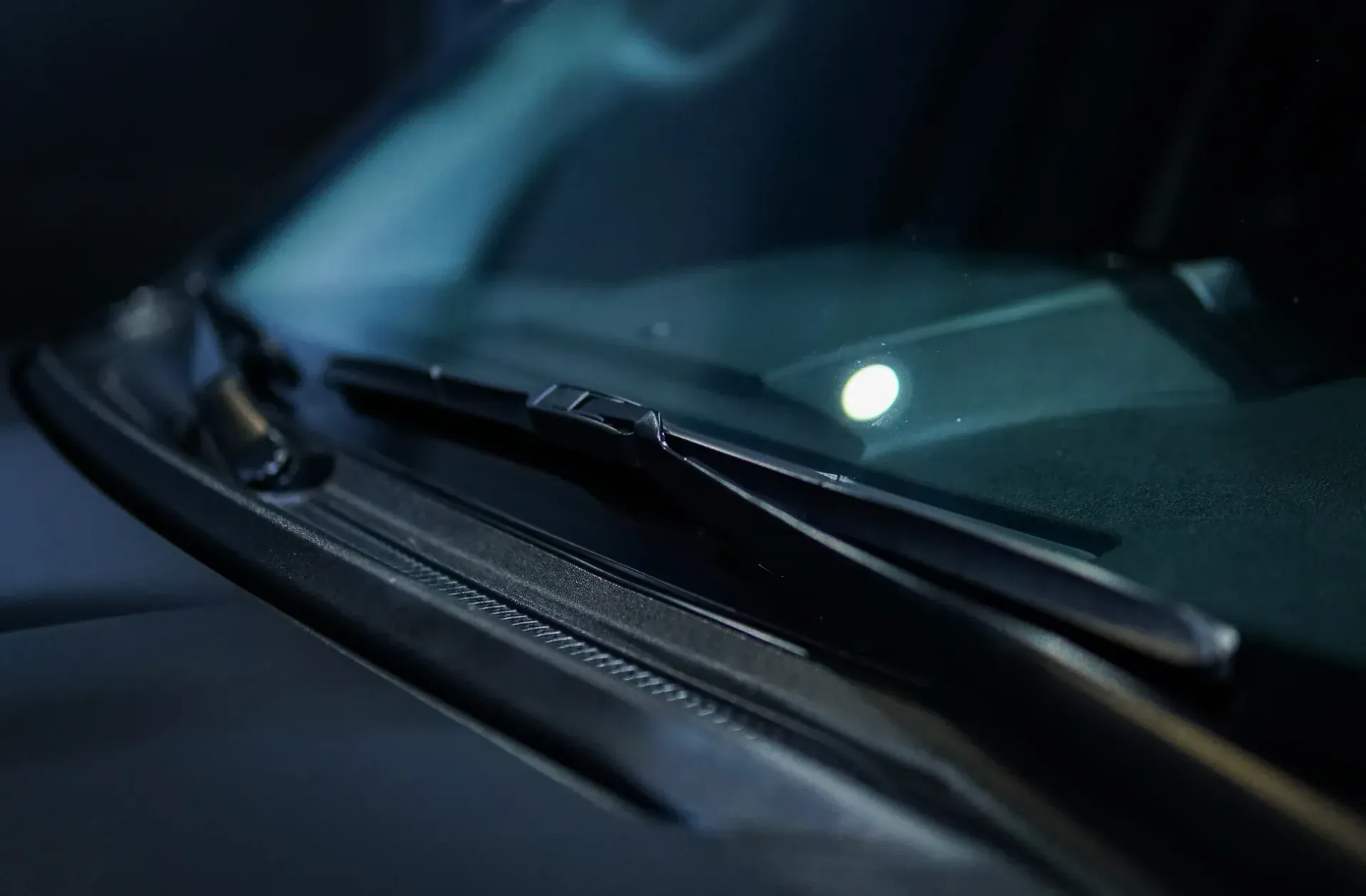 Car's interior view showing windshield, windshield wiper, and a small illuminated light.