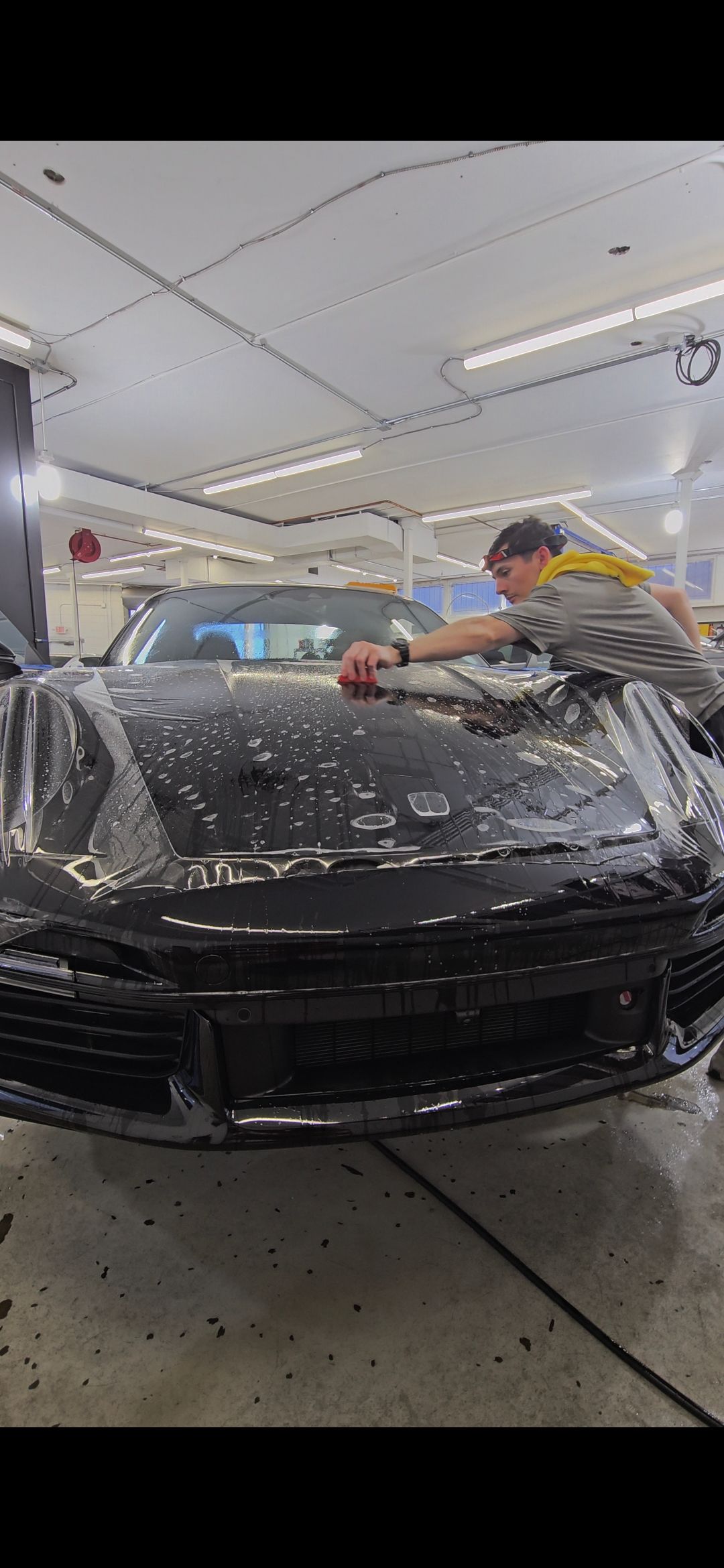 A person washes a black car in a garage.