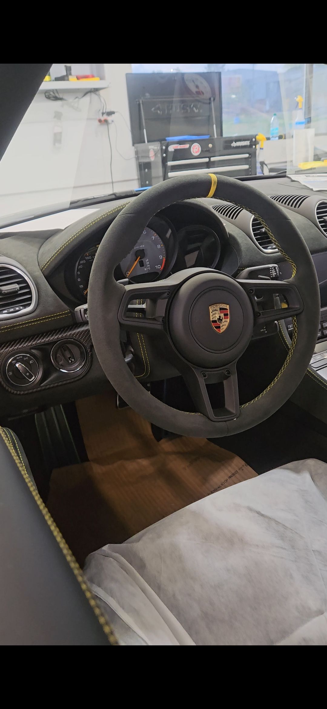 Interior view of a Porsche sports car with a black steering wheel and brown seat.