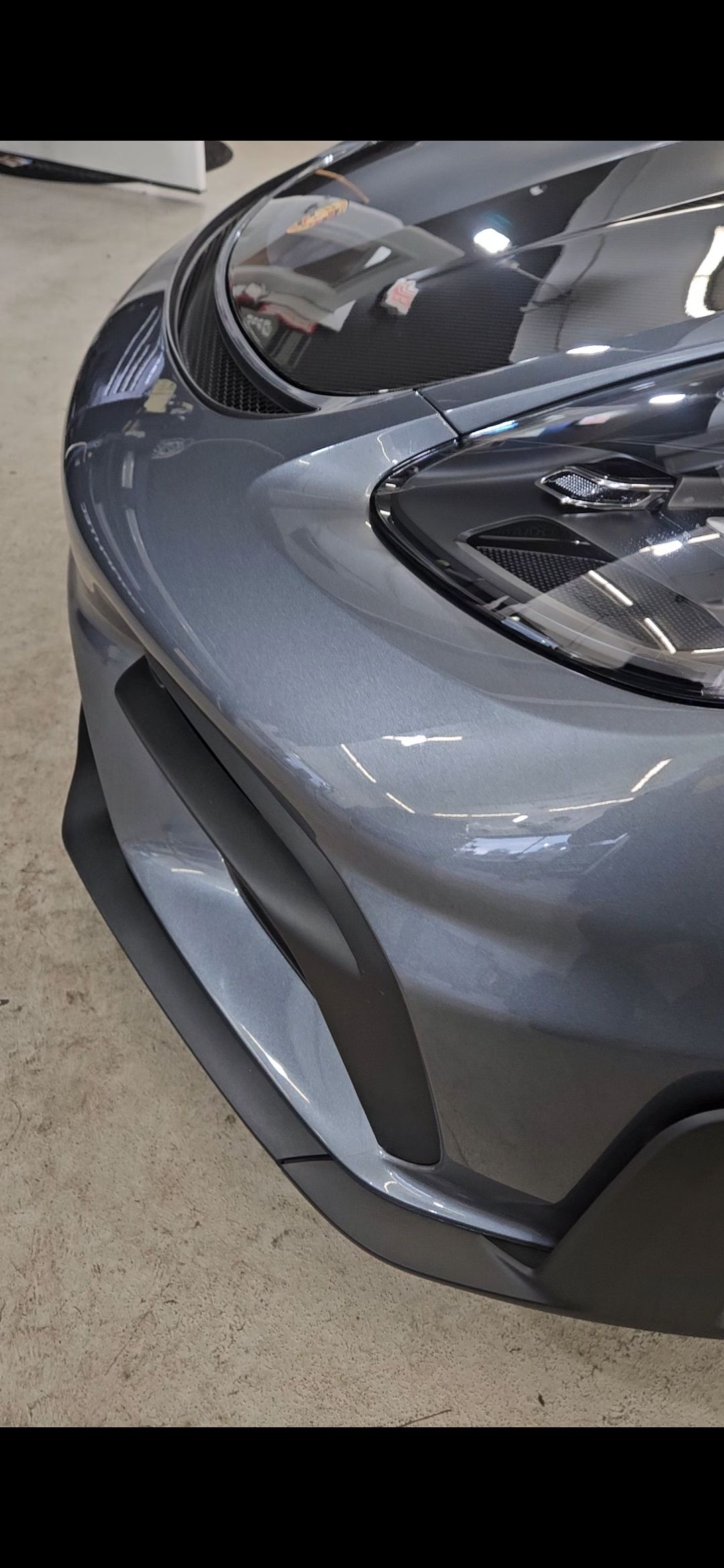 Gray sports car front quarter panel with a headlight.