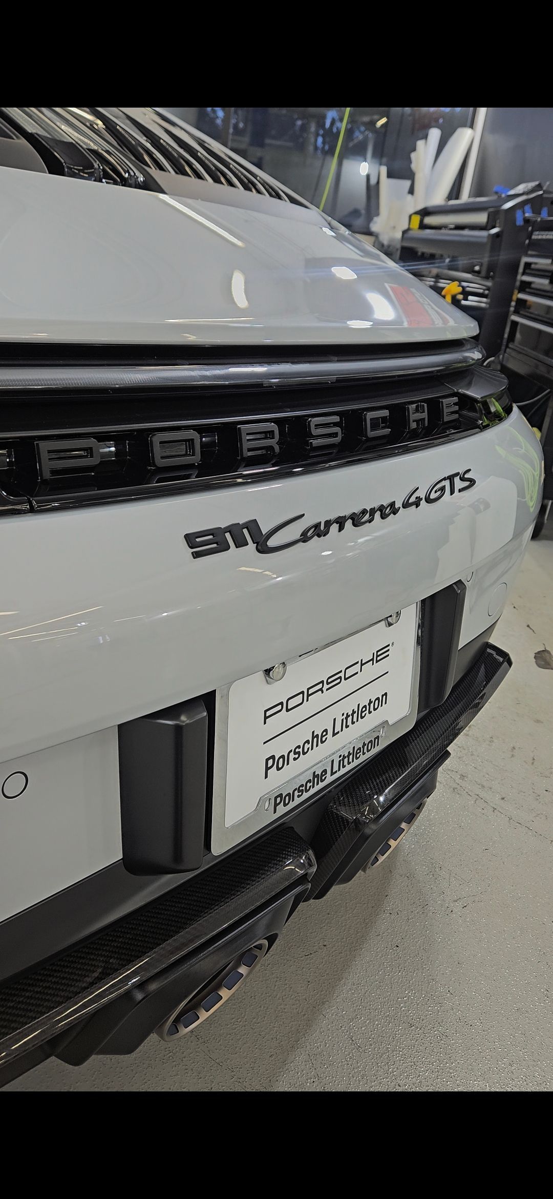 Rear view of a light gray Porsche 911 Carrera GTS. Black lettering and accents are visible.