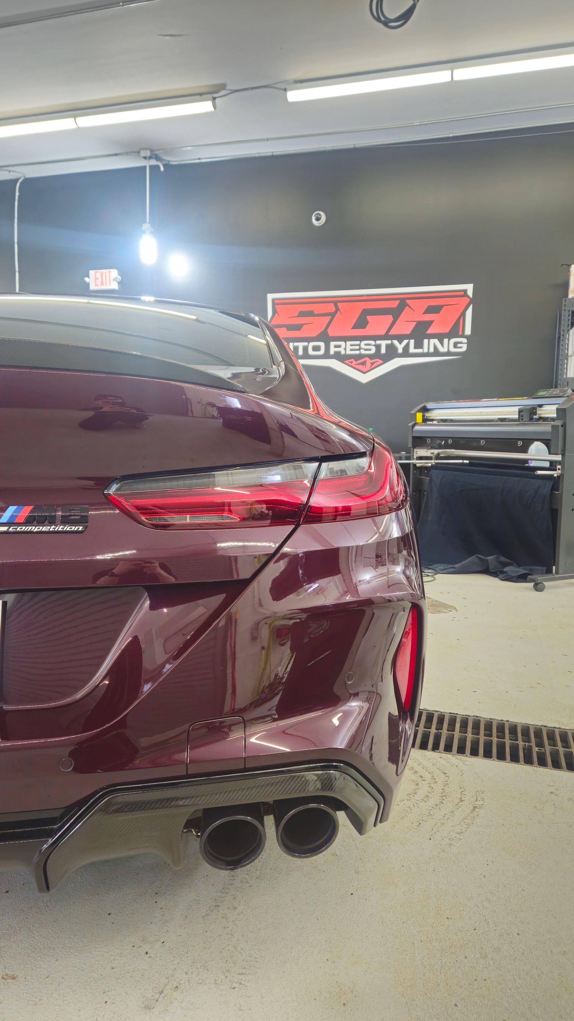 Burgundy BMW M car rear, parked inside a garage. 