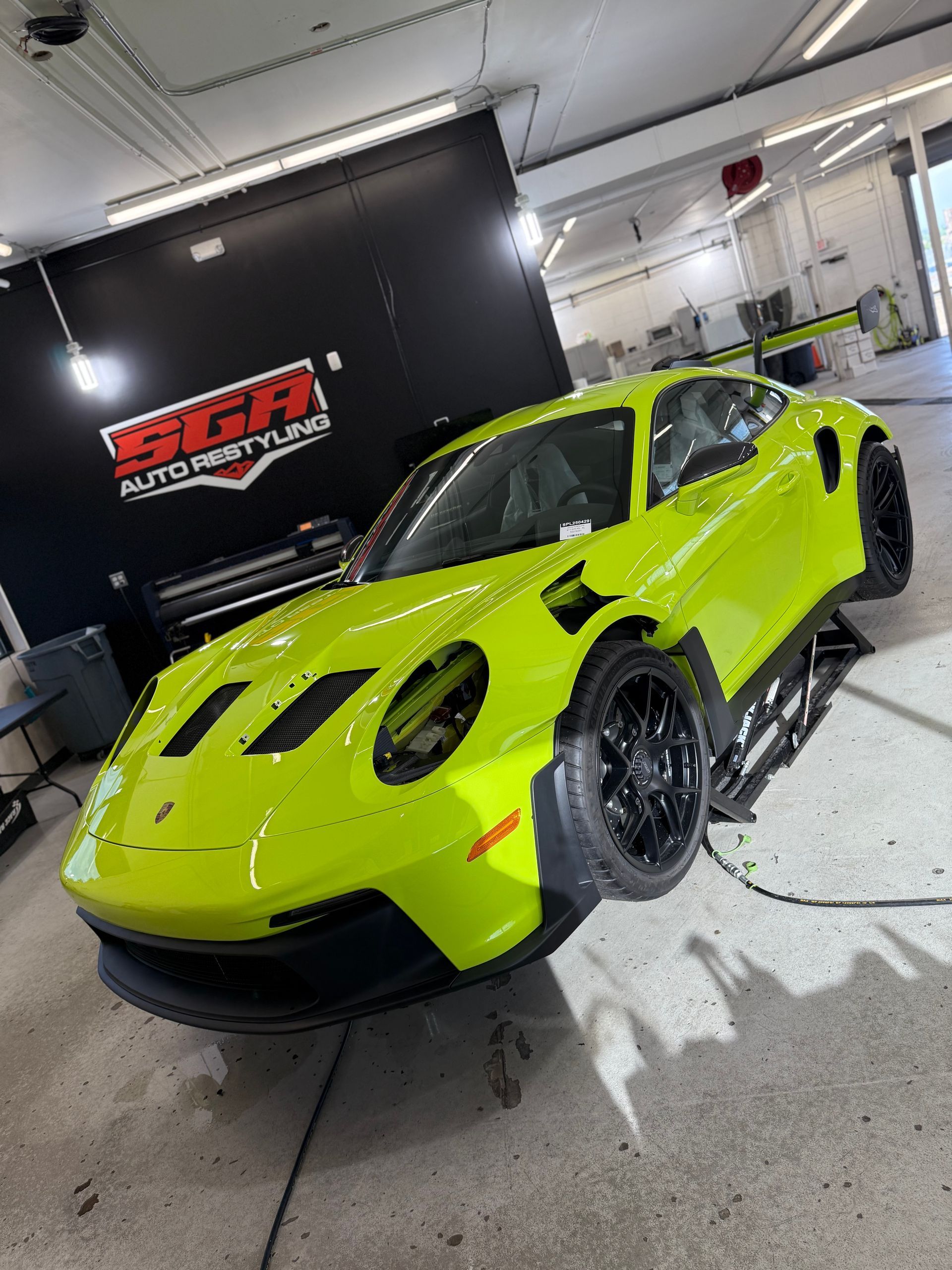 Bright yellow sports car inside a garage. Black wheels and front lip. 
