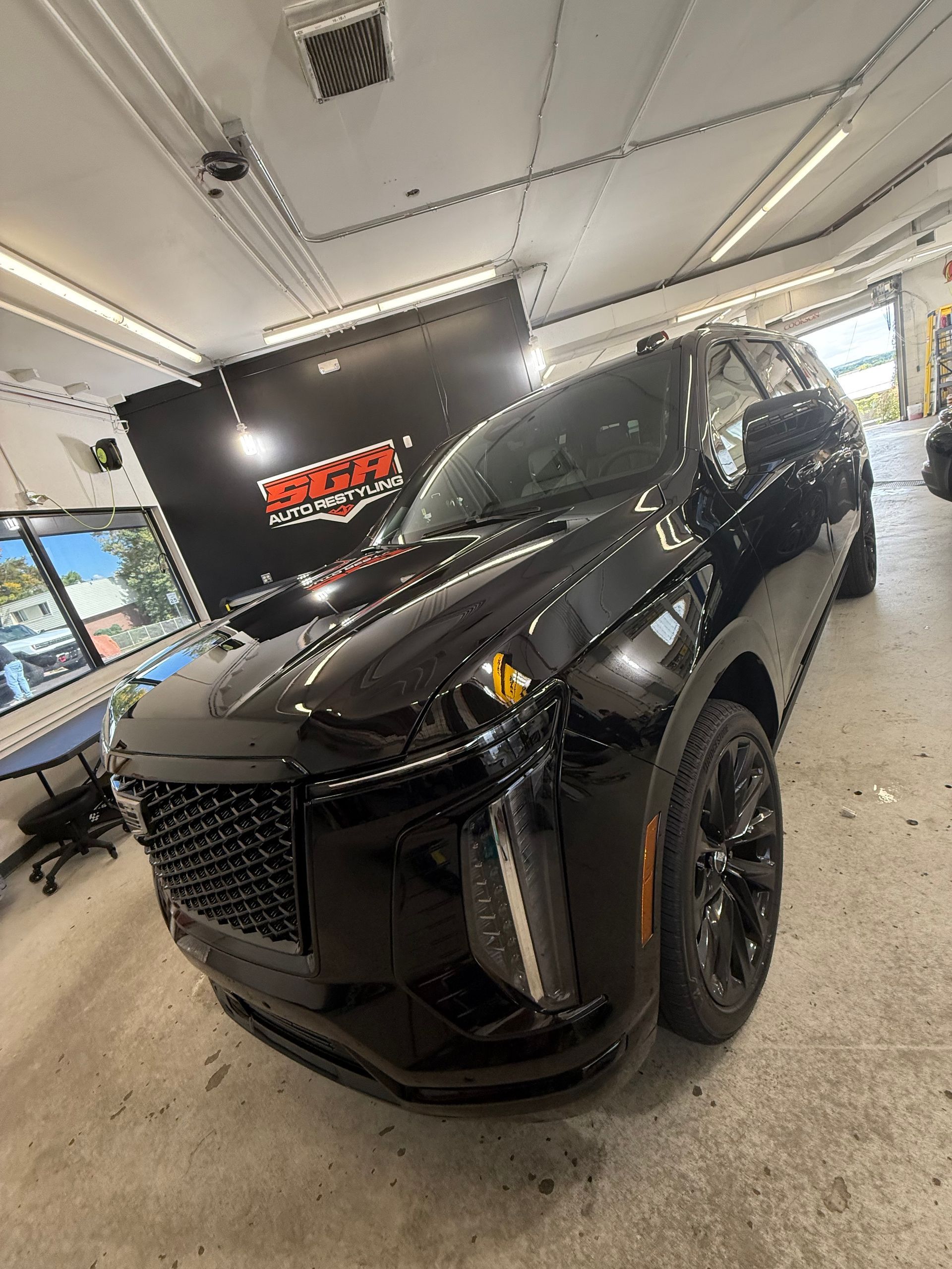 Black SUV parked in a shop with a blacked-out front grille.