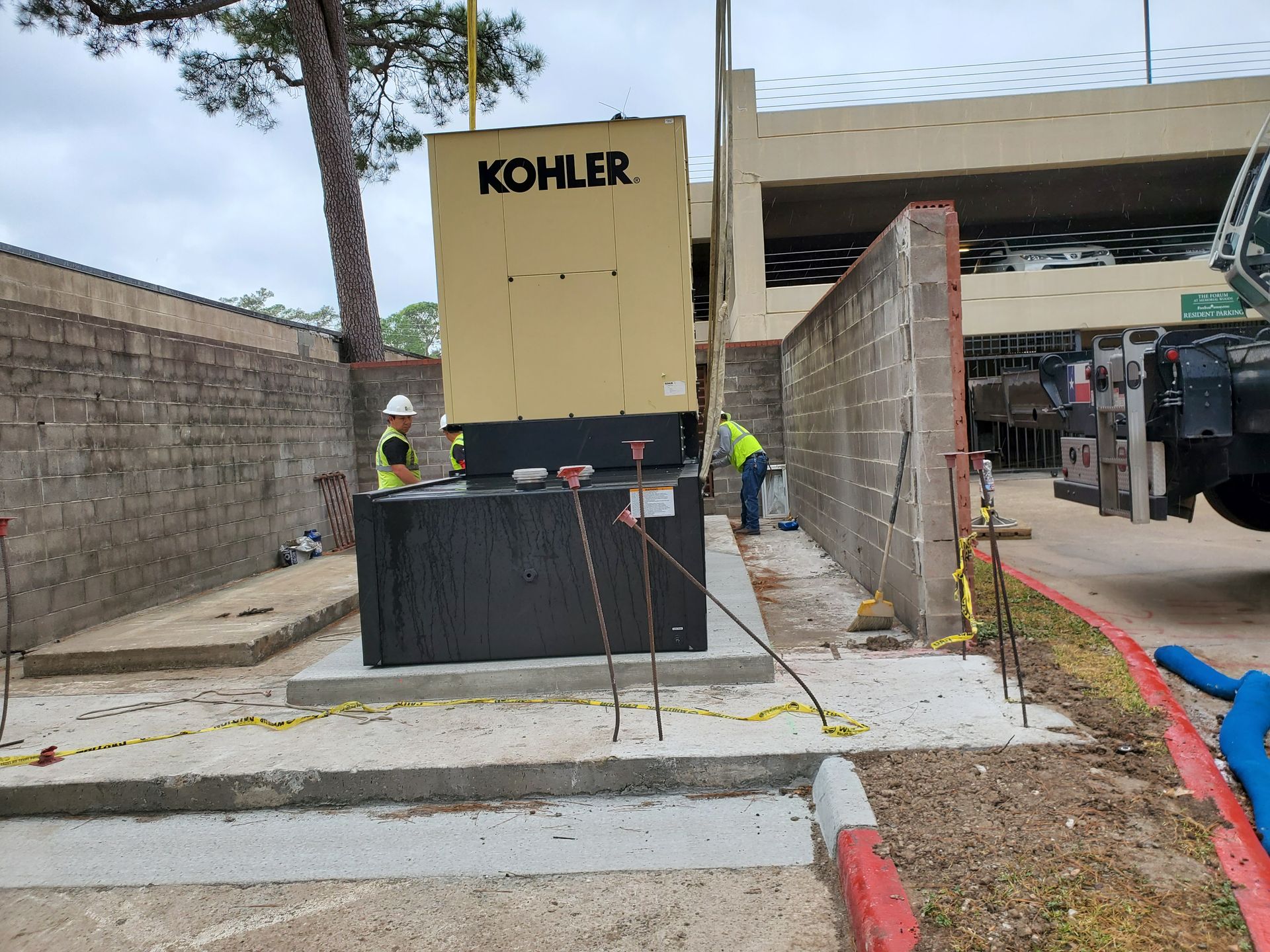 A white generator is sitting on the side of a brick building.