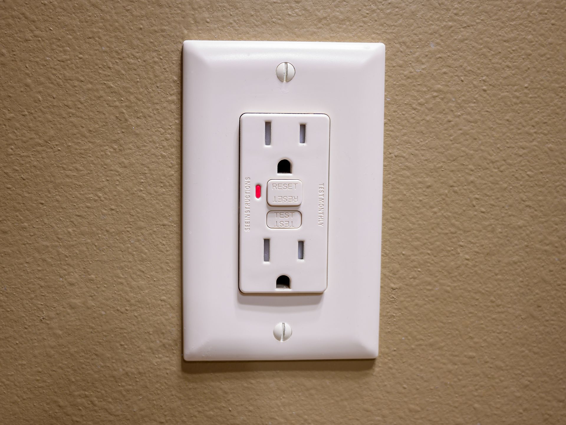 A white electrical outlet with a red light on it