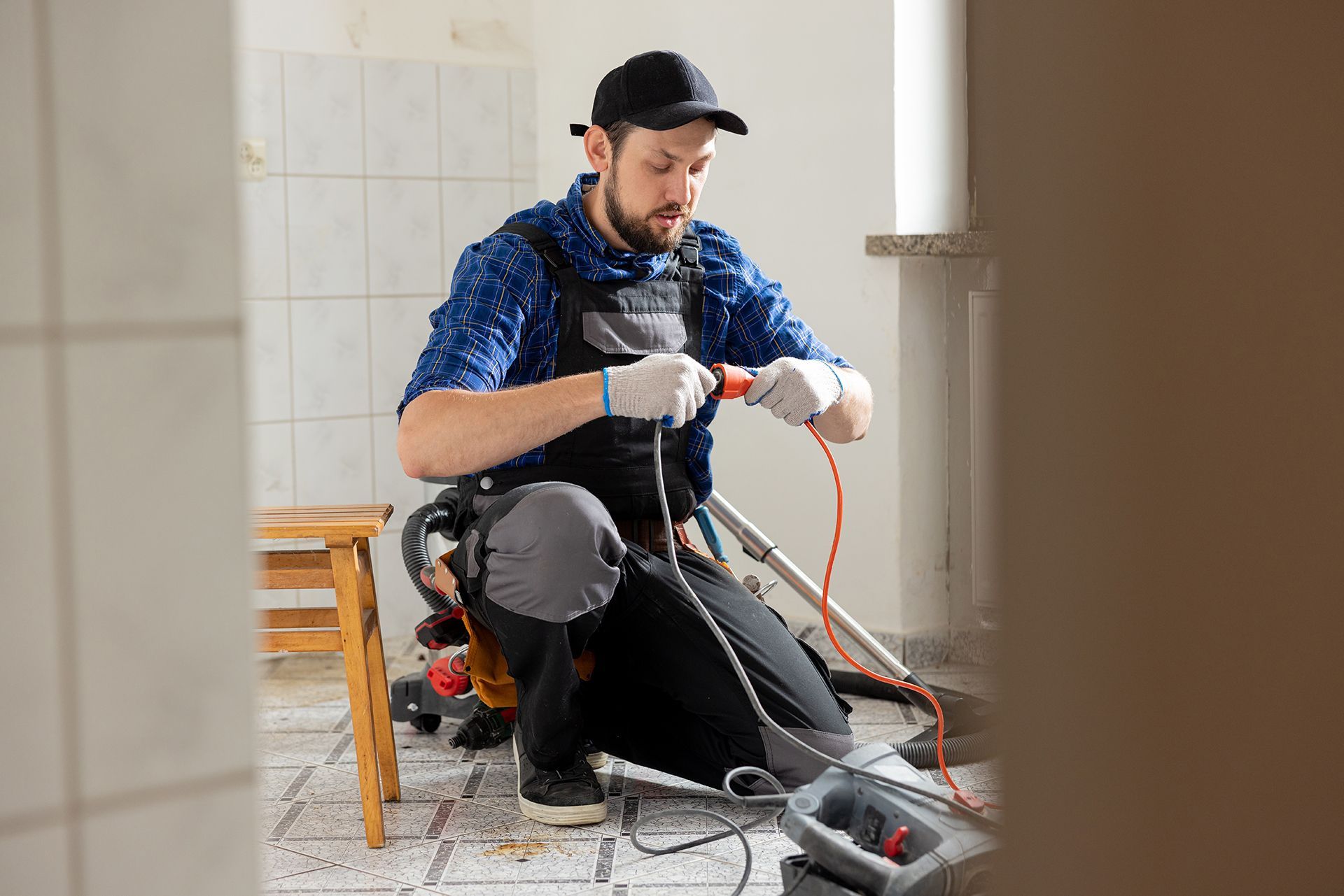 A man is kneeling on the floor fixing a vacuum cleaner