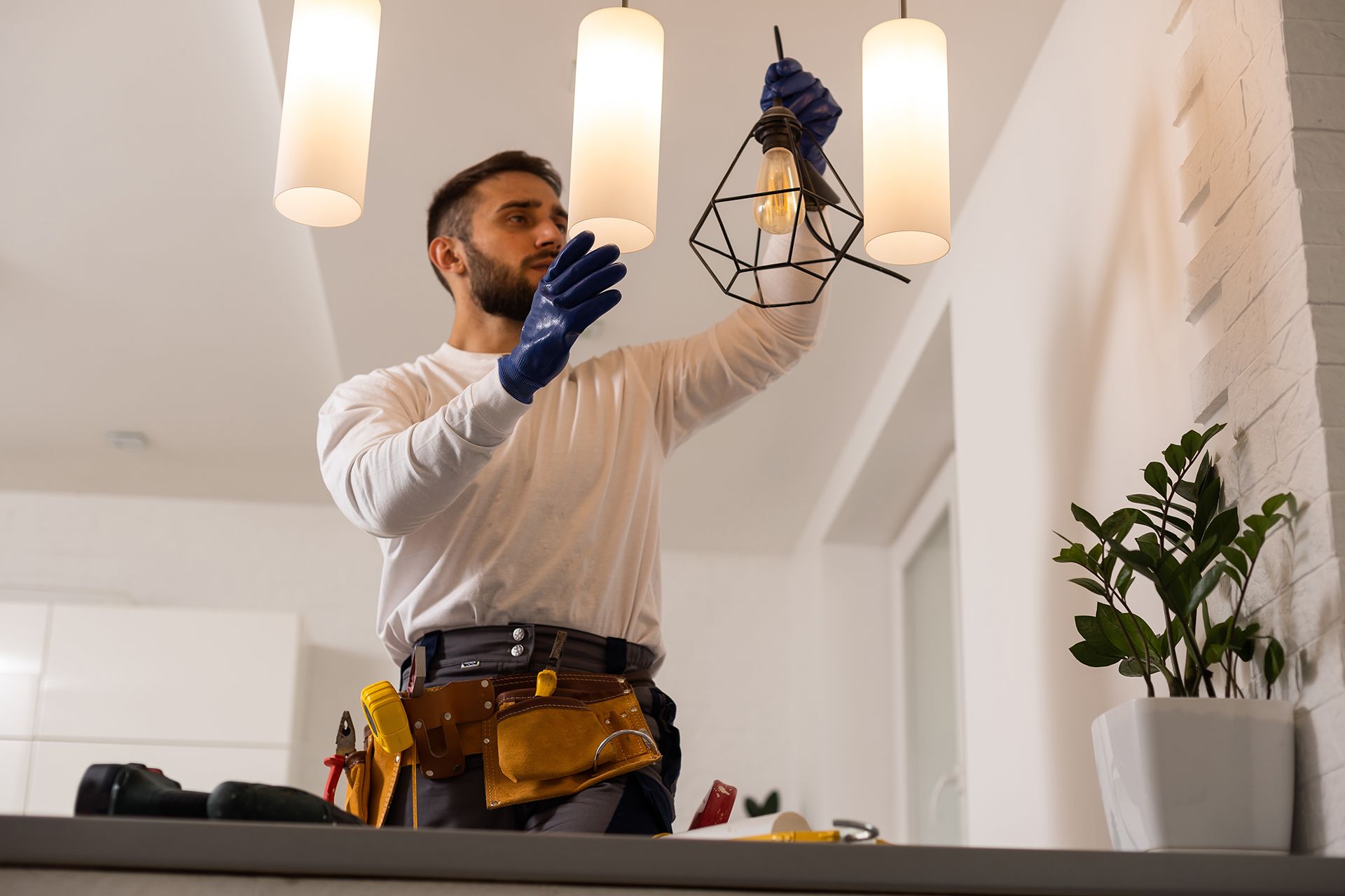 A man is fixing a light fixture in a living room