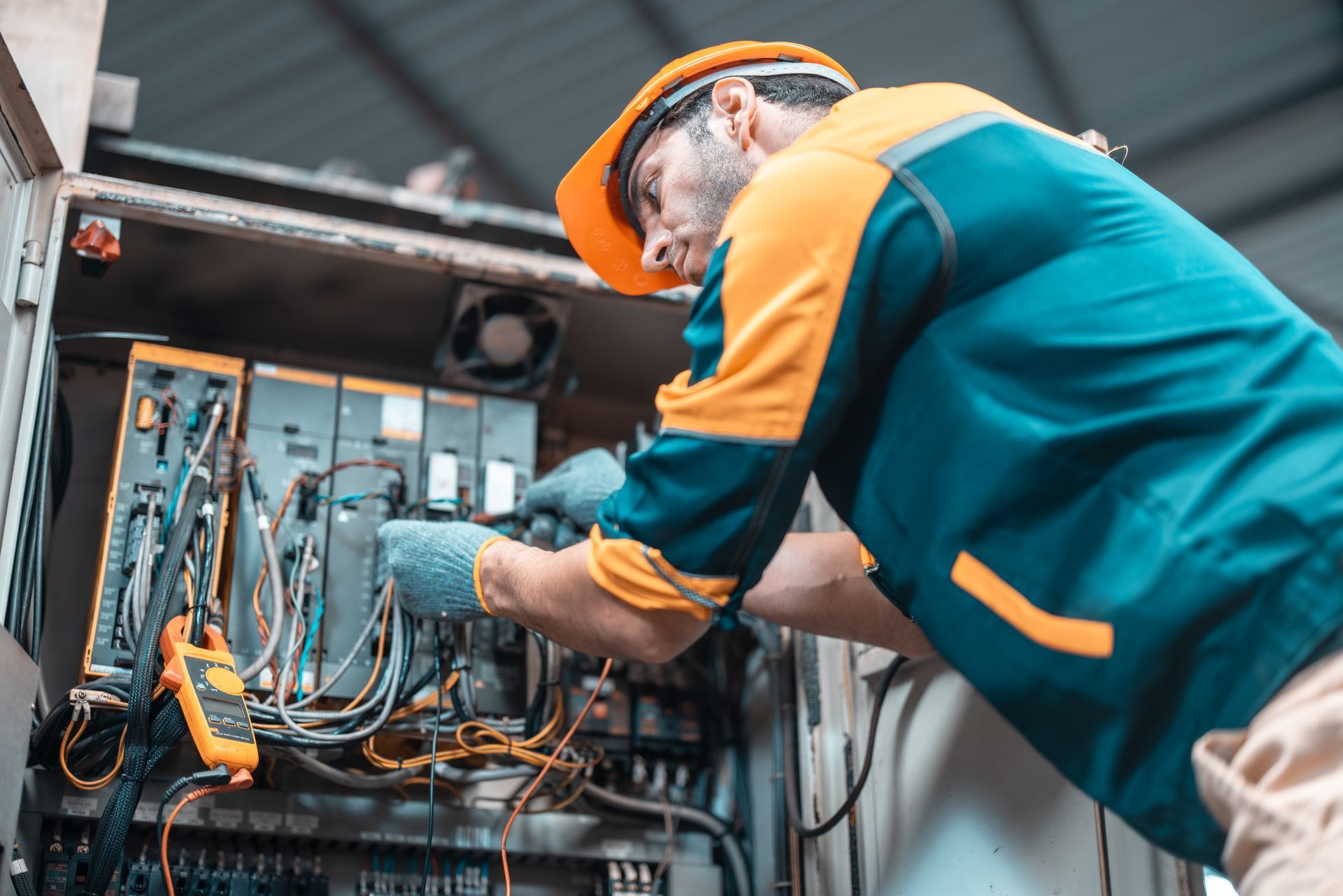 A man in a hard hat is working on an electrical box