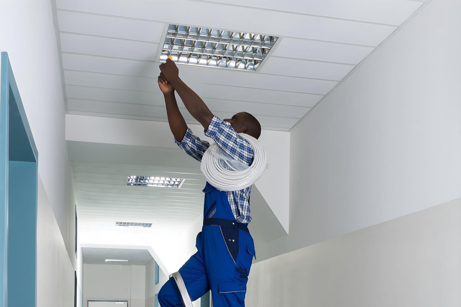 A man is hanging a light on the ceiling in a hallway
