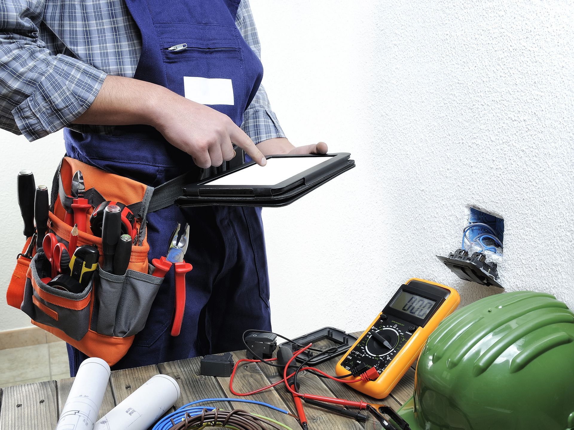 A man with a tool belt is using a tablet