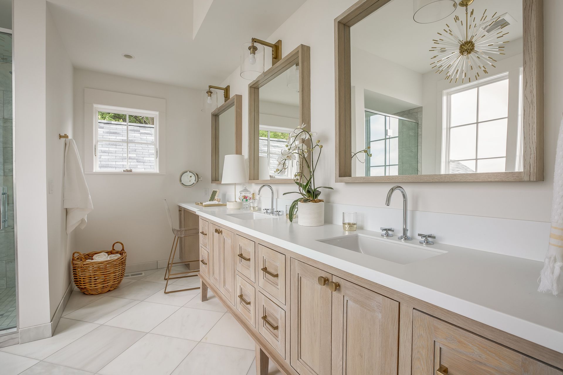 Bright white bathroom with double sinks, wooden cabinets, and large mirrors.