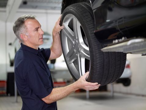 Mechanic changing tire position in auto repair shop