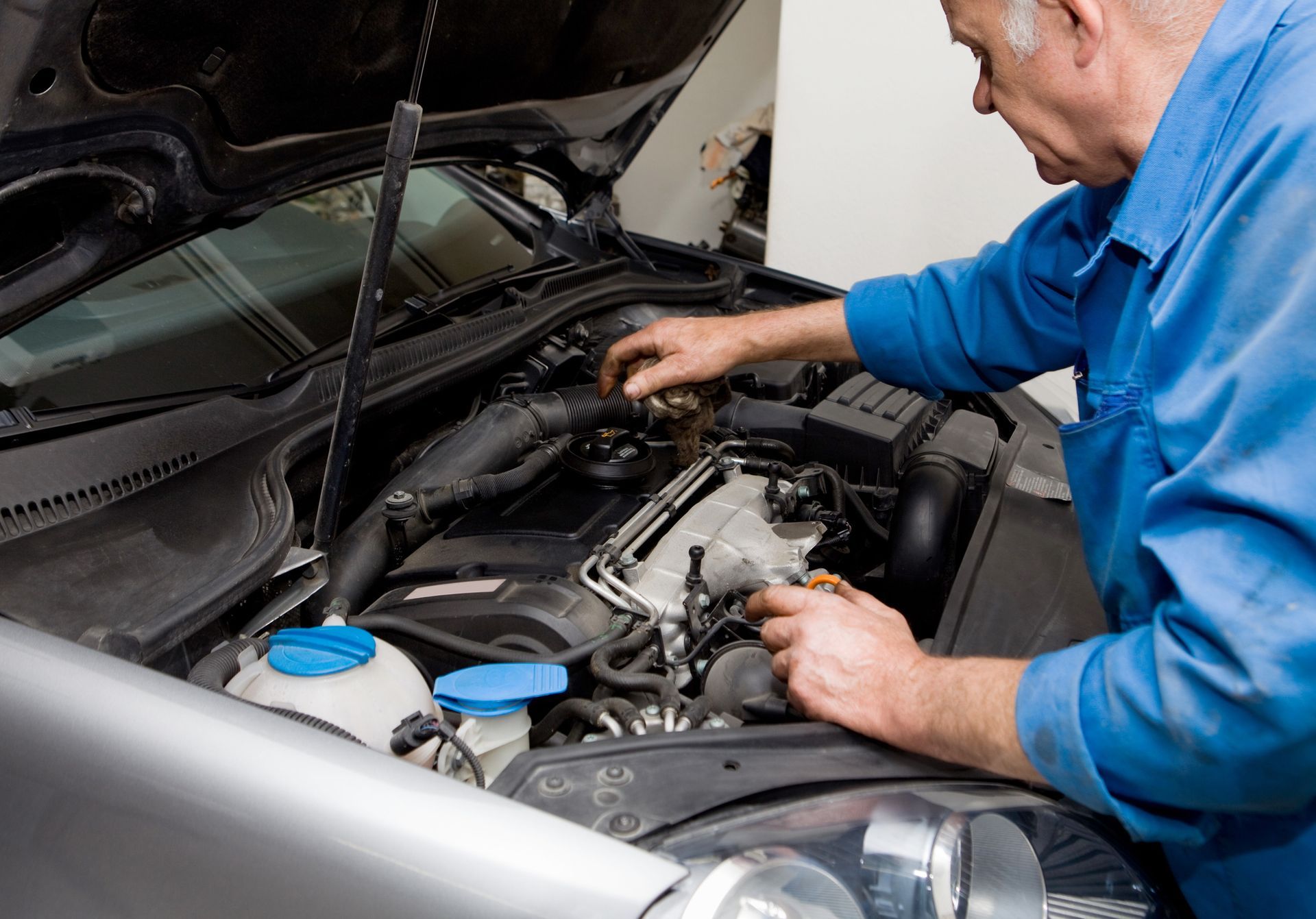 Auto repair mechanic inspecting car engine for maintenance issues