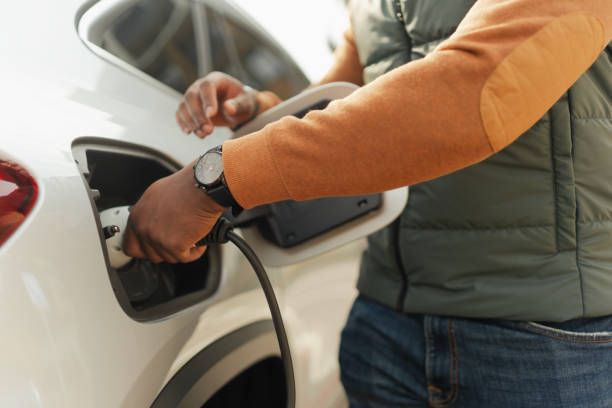 A man is charging his electric car at a charging station.