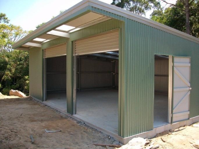 A Green Building With A White Door Is Sitting On Top Of A Dirt Hill — Just Sheds In Sunshine Coast, QLD