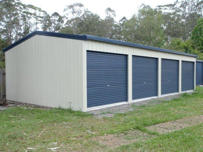 A Row of Garage Doors Are Lined Up in a Grassy Area — Just Sheds In Kunda Park, QLD