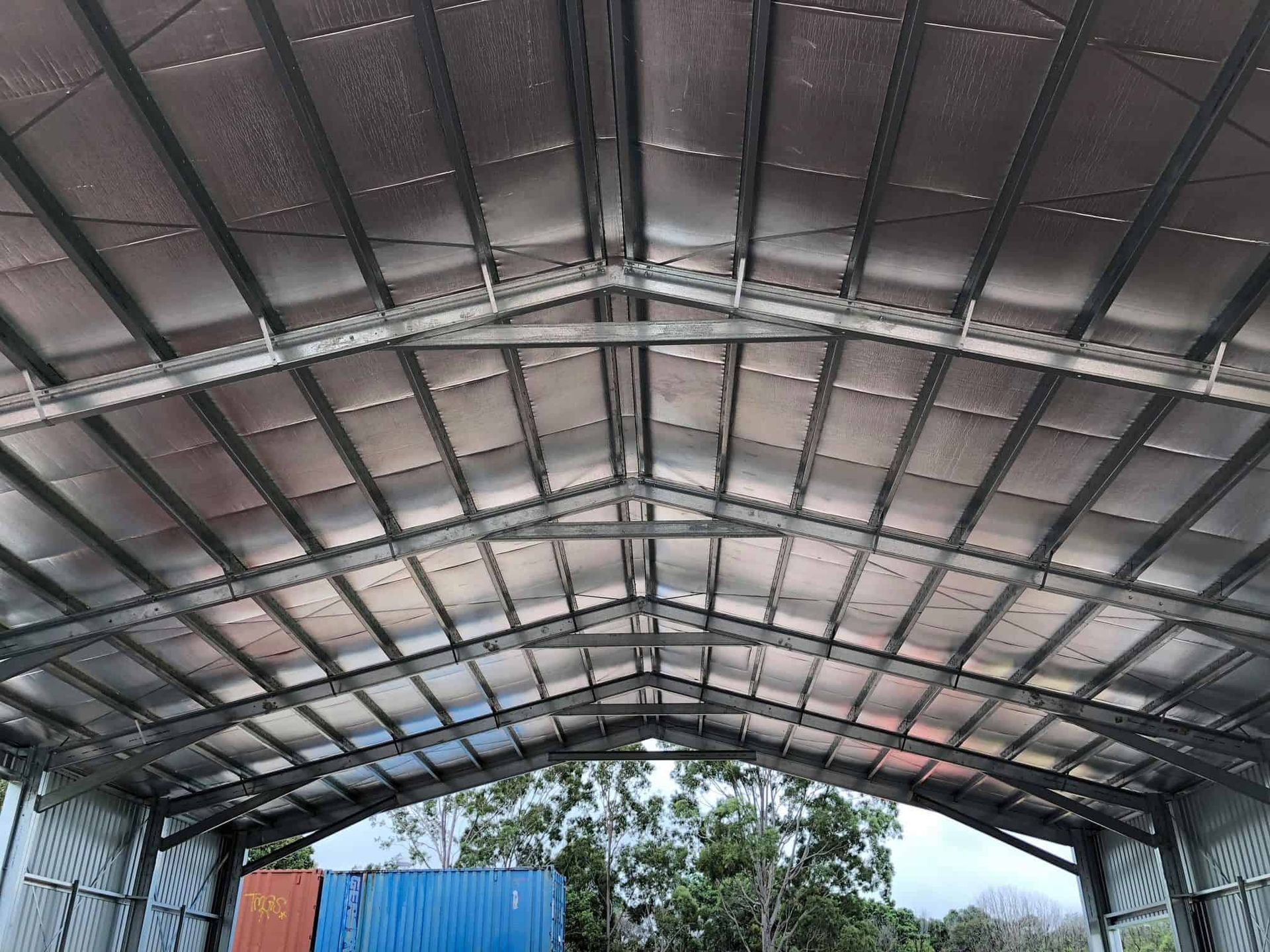 A blue container is sitting inside of a large metal building. — Just Sheds In Kunda Park, QLD