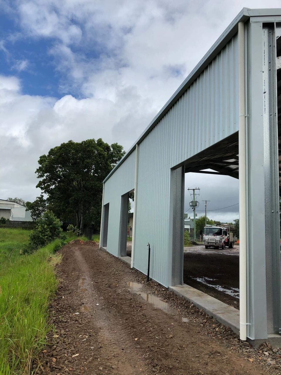A Car Is Parked In A Garage Next To A Dirt Road — Just Sheds In Kunda Park, QLD