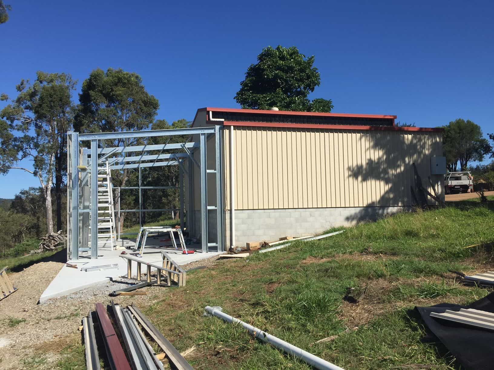 A building is being built on top of a grassy hill. — Just Sheds In Kunda Park, QLD