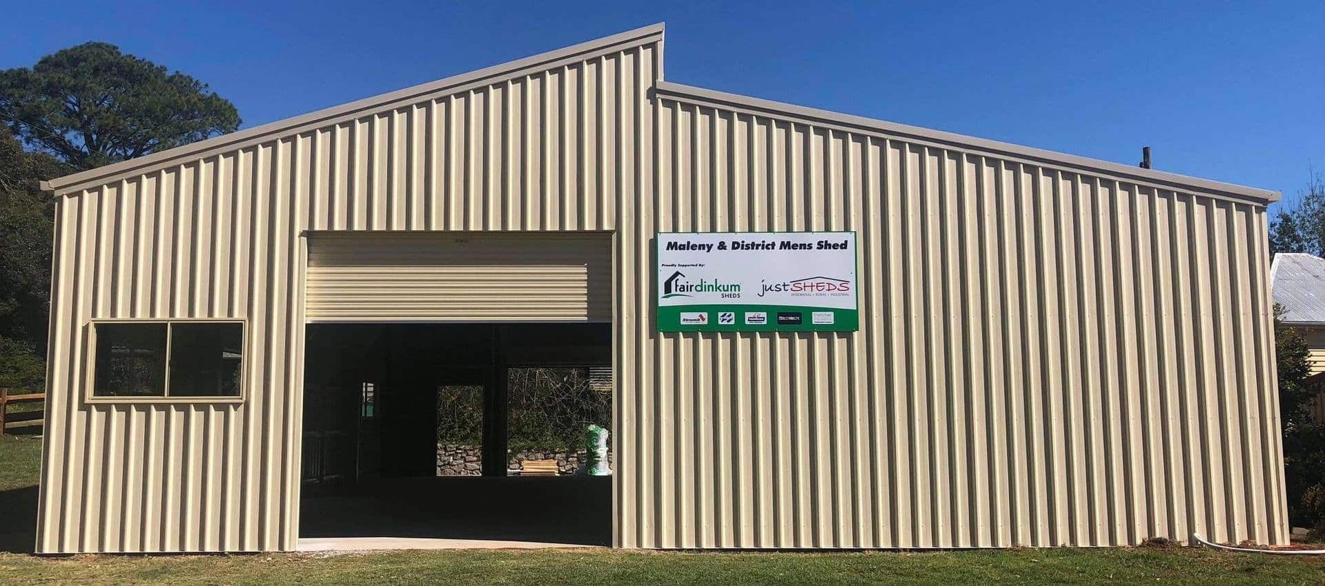 A large metal building with a sign on the side of it. — Just Sheds In Kunda Park, QLD