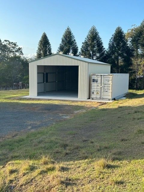 A White Building With A Shipping Container In Front Of It — Just Sheds In Brendale, QLD