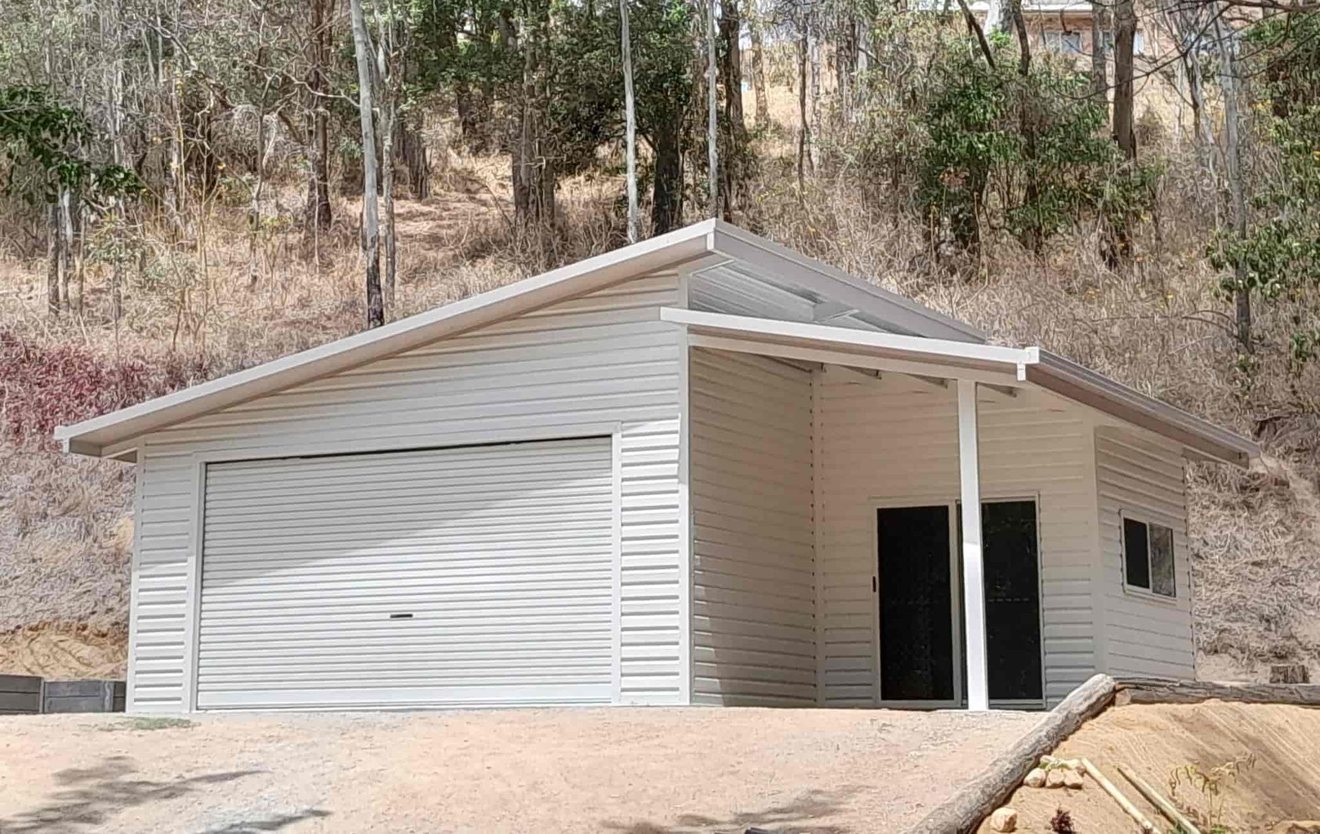 A White Garage With A Covered Porch Is Sitting On Top Of A Dirt Hill — Just Sheds In Brendale, QLD
