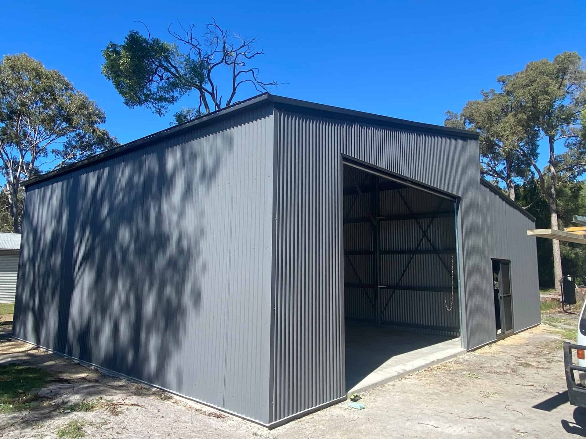 A large gray metal building with a large sliding door. — Just Sheds In Kunda Park, QLD