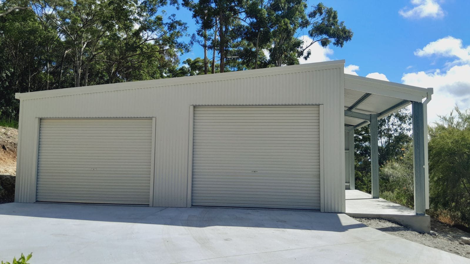 A white garage with two roller doors and a porch. — Just Sheds In Kunda Park, QLD