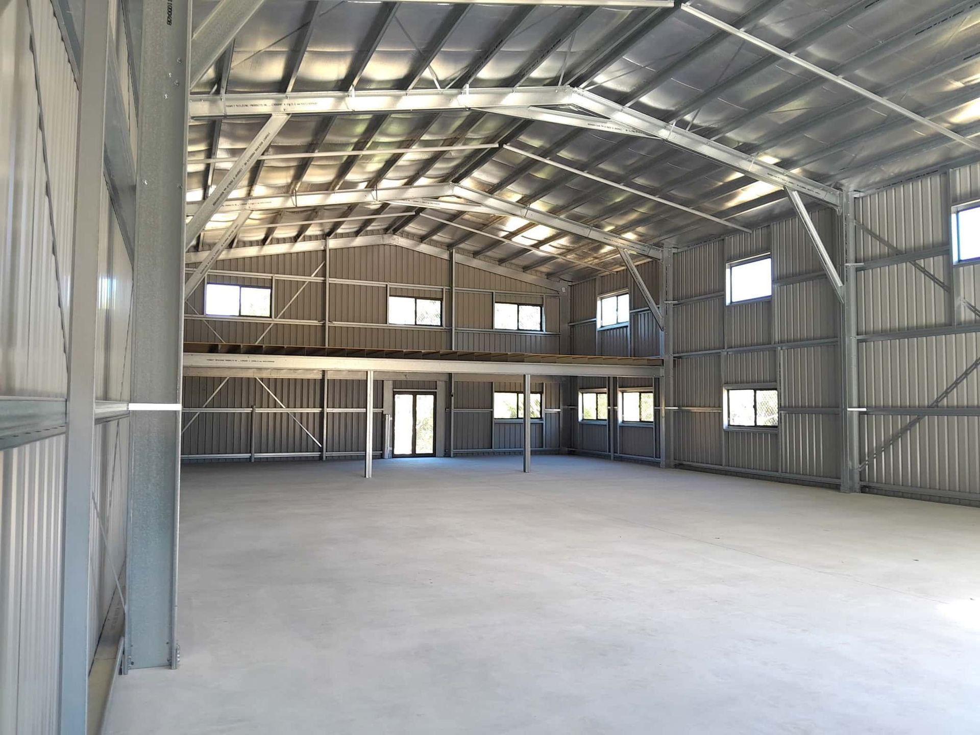 A large empty warehouse with a metal roof and concrete floor. — Just Sheds In Kunda Park, QLD