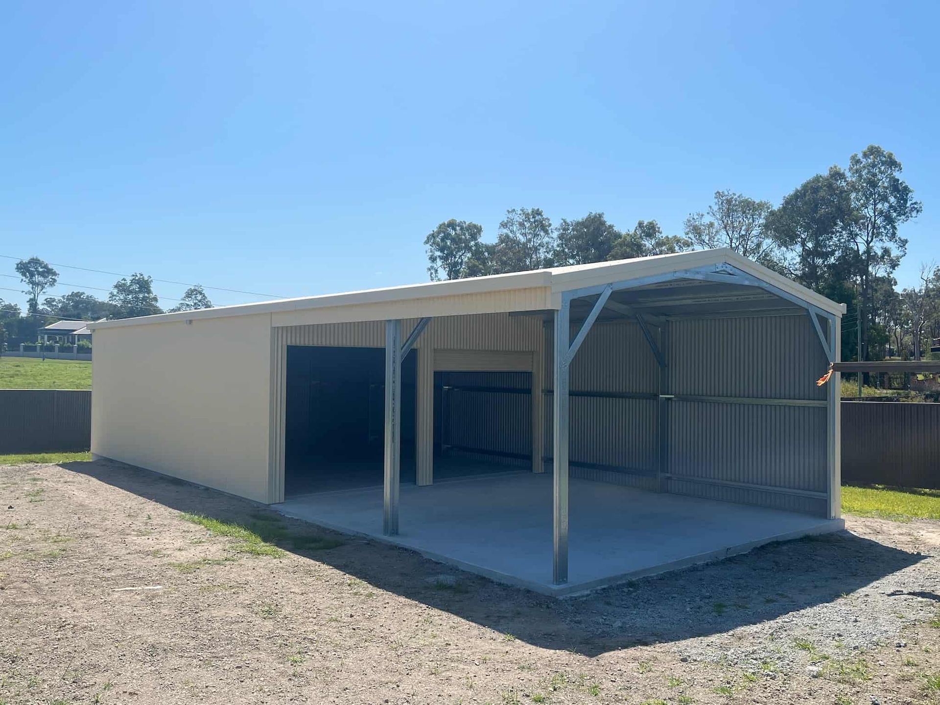 A garage with a canopy over it is sitting in the middle of a dirt field. — Just Sheds In Kunda Park, QLD