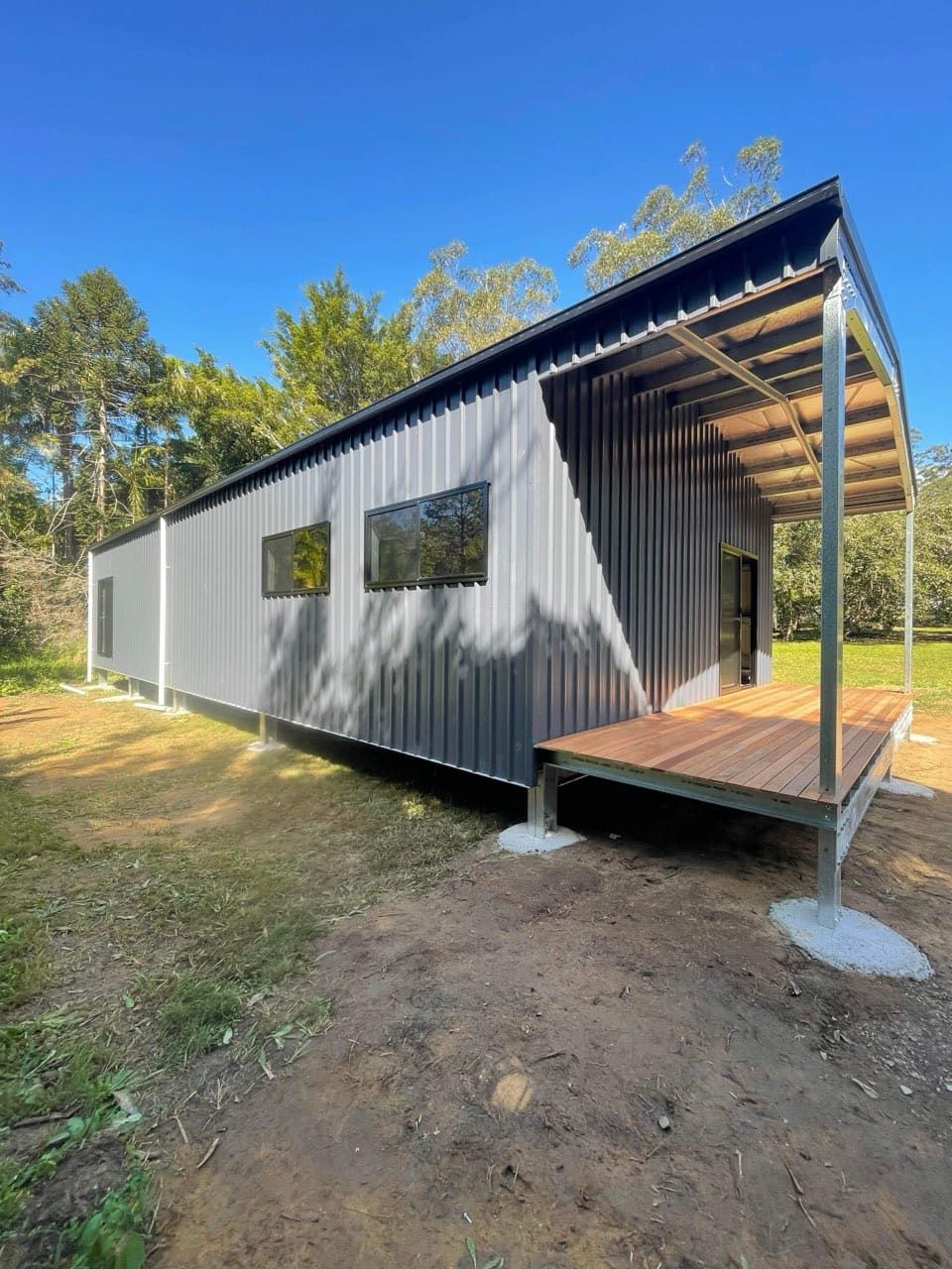 A small house with a porch and a roof is sitting in the middle of a field. — Just Sheds In Kunda Park, QLD