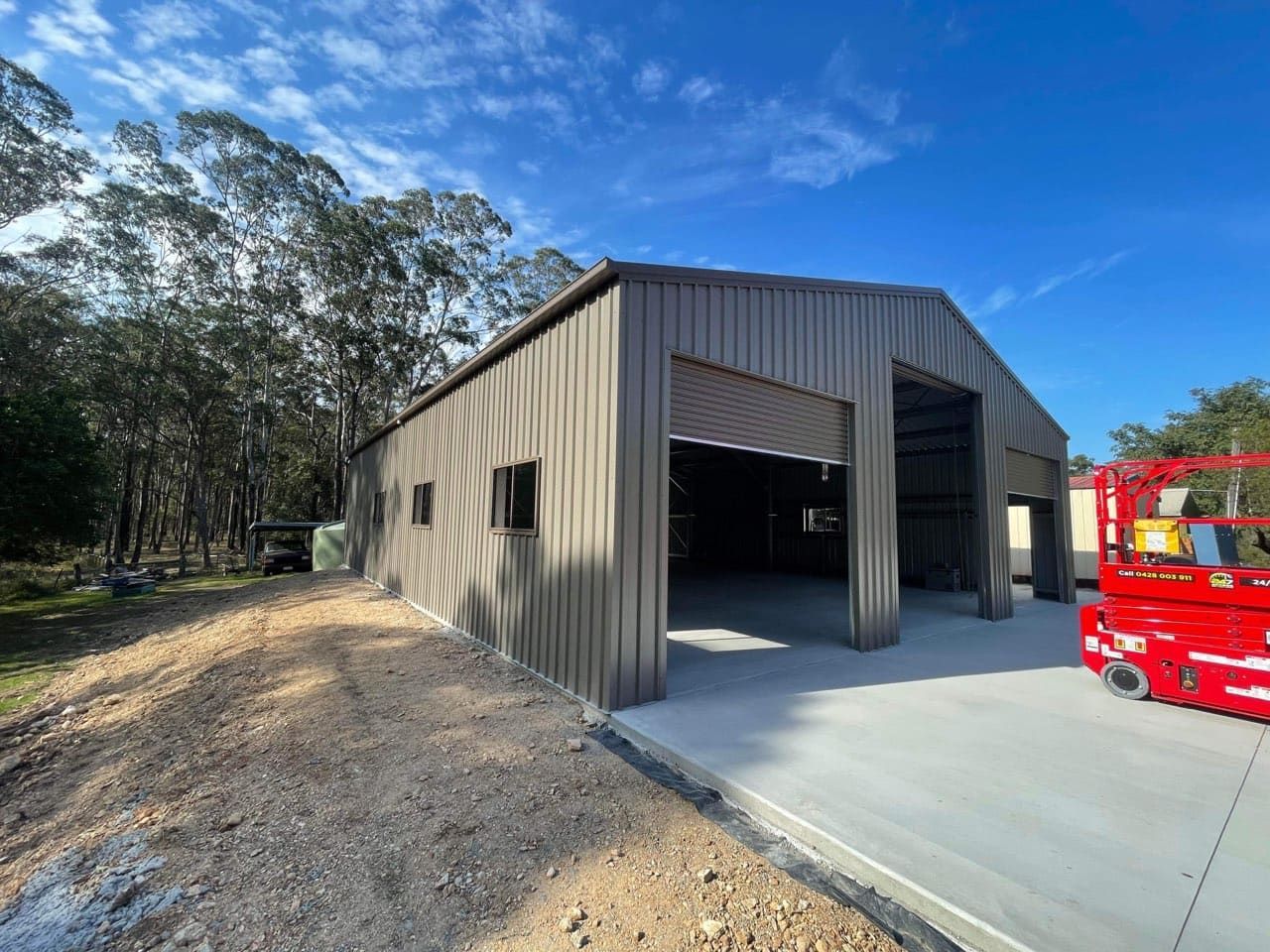 A large metal building with a large garage door is being built. — Just Sheds In Kunda Park, QLD