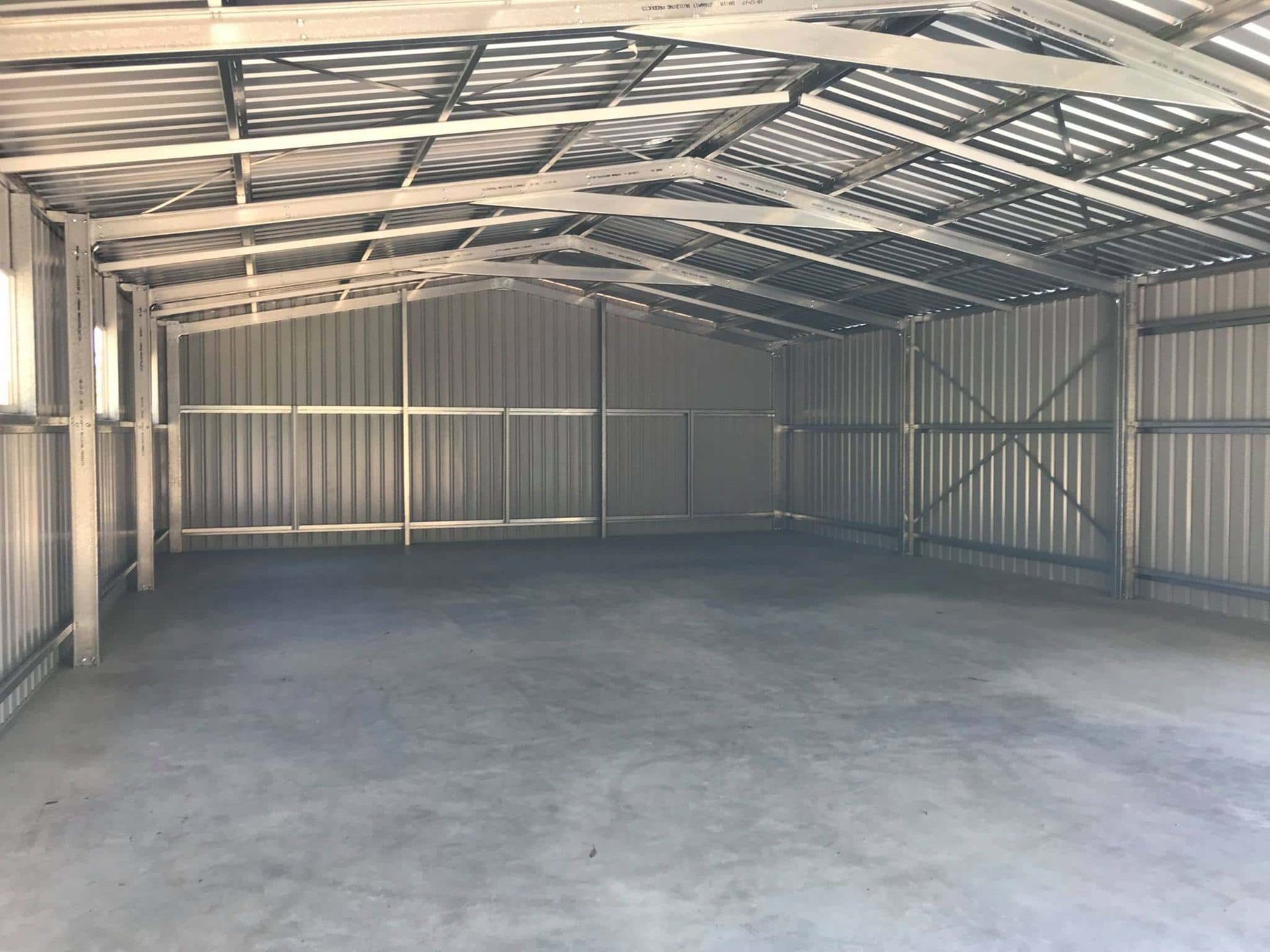 The inside of an empty metal building with a concrete floor. — Just Sheds In Kunda Park, QLD