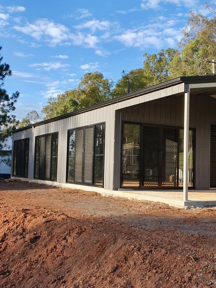 A large house with a lot of windows is sitting on top of a dirt hill. — Just Sheds In Brendale, QLD