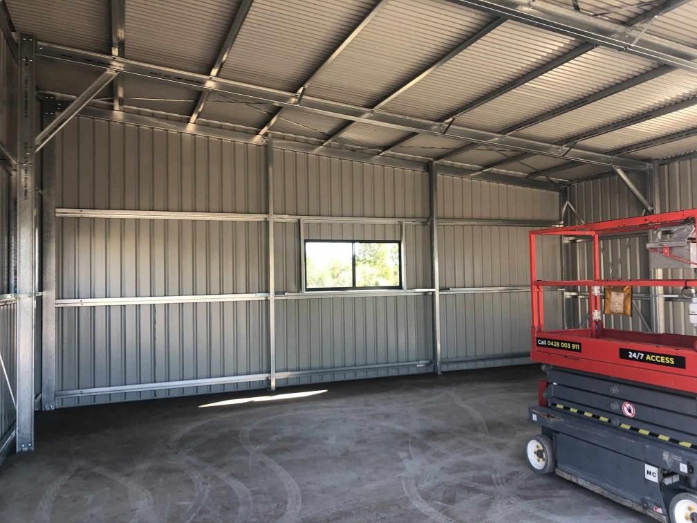 A Red Scissor Lift Is Parked Inside Of A Building — Just Sheds In Kunda Park, QLD