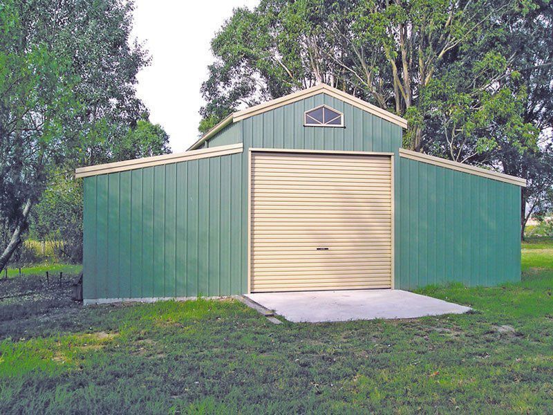 A Green Barn With a Tan Door is in the Middle of a Grassy Field — Just Sheds In Kunda Park, QLD
