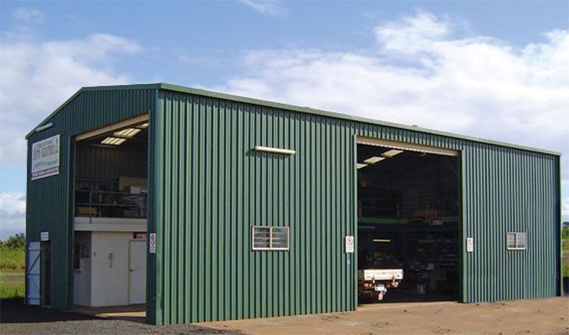 A Large Green Metal Building With a Lot of Windows and Doors — Just Sheds In Kunda Park, QLD