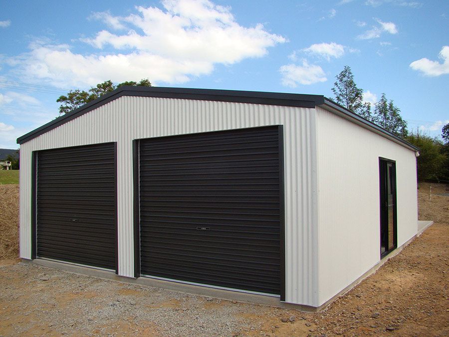 A White Garage With Black Doors and a Blue Sky in the Background — Just Sheds In Kunda Park, QLD