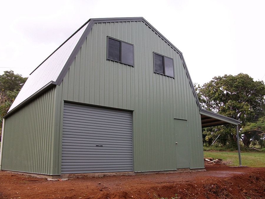 A Green Barn With a Gray Garage Door and a White Roof — Just Sheds In Kunda Park, QLD