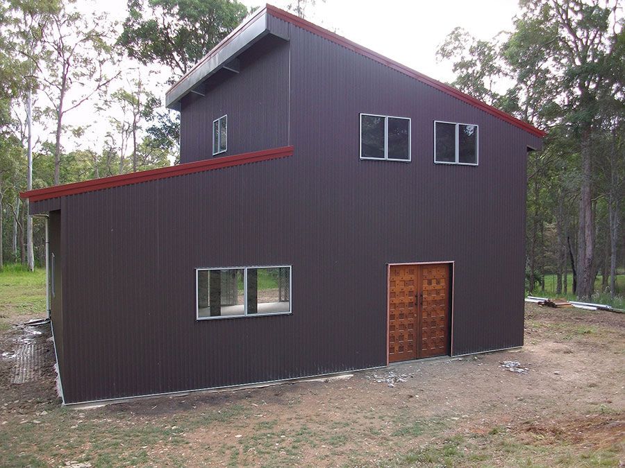 A Brown Building With a Red Roof and a Wooden Door  — Just Sheds In Kunda Park, QLD