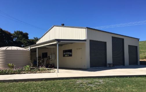 A Garage With a Porch and a Water Tank in Front of It — Just Sheds In Kunda Park, QLD