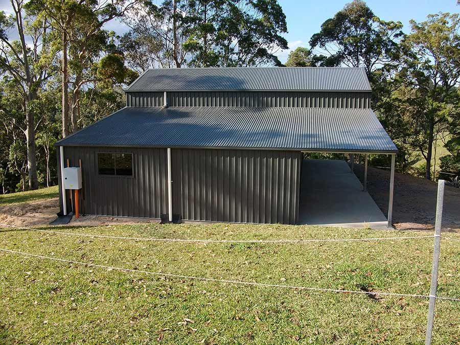 A Large Metal Building With a Driveway Leading  — Just Sheds In Kunda Park, QLD