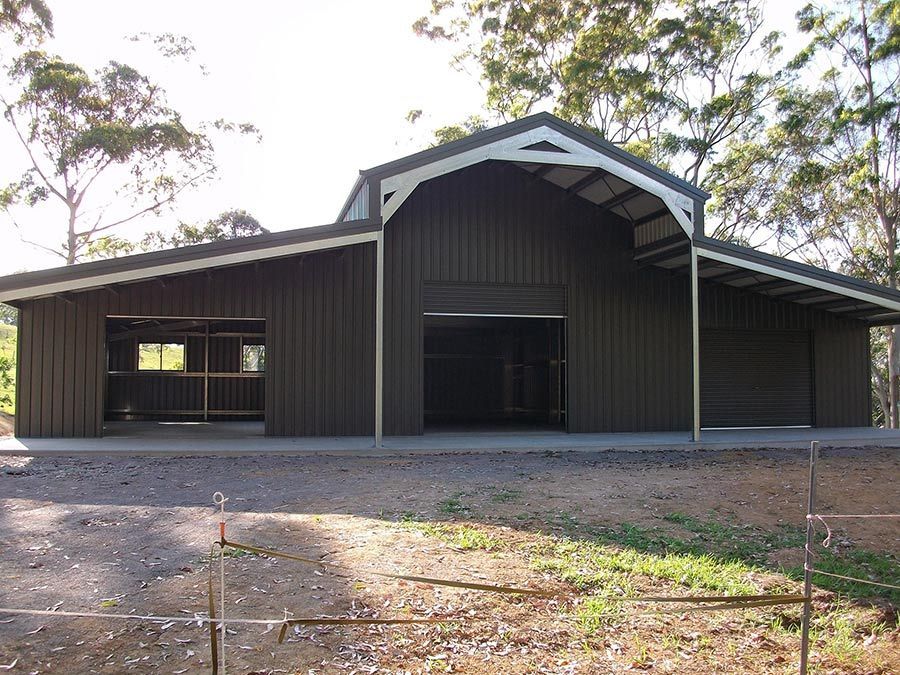 A Large Barn With a White Roof is Surrounded by Trees — Just Sheds In Kunda Park, QLD