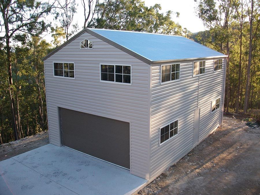 A large white building with a blue roof is surrounded by trees